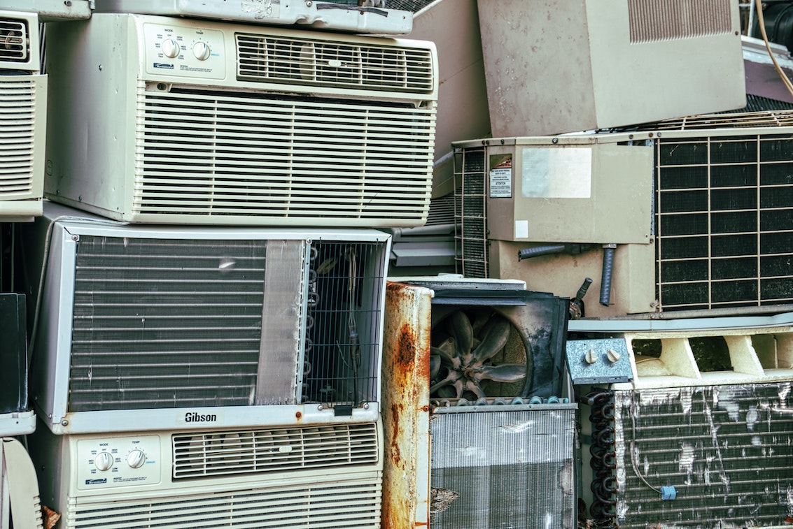A stack of old air conditioning units, some rusted and broken
