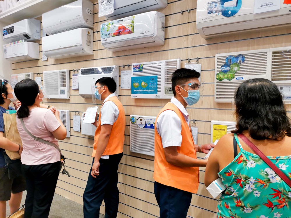 Shoppers and store employees discuss air conditioners in an appliance store in the Philippines.