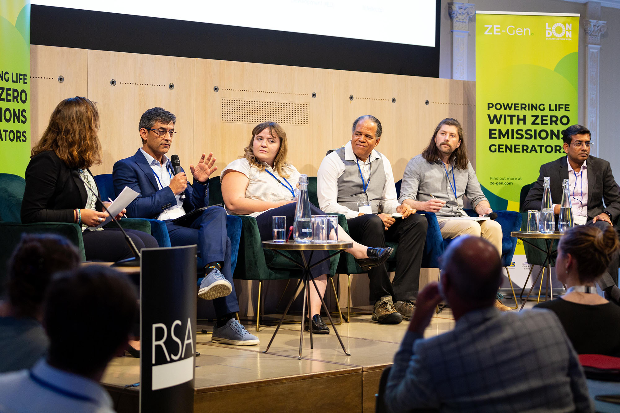 Six people take part in a panel discussion on a small stage.